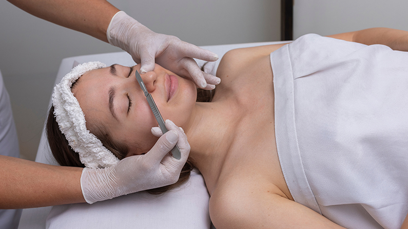 young woman lying on a stretcher in an aesthetic center performing beauty treatment and facial aesthetics with dermapen and dermaplaning techniques